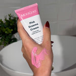 Hand holding a tube of MooGoo Pink Eczema Cream with visible pink cream on hand.